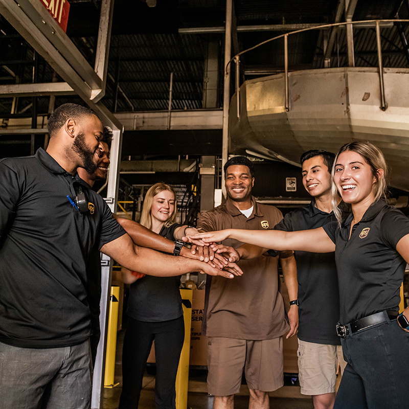 A group of upsers in a sorting facility, smiling as they break a huddle.